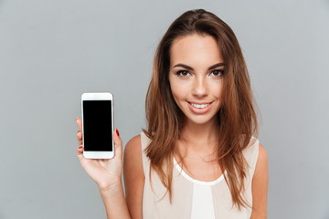 Portrait of a smiling woman showing blank smartphone screen