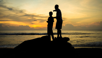 Father & Son Bonding and Pointing to the Horizon During an Orange Beach Sunset 