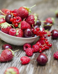Ripe fruit and berries in a white cup on a wooden table