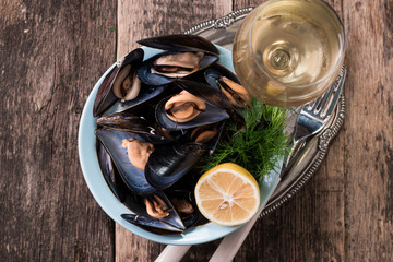 Mussels in copper cooking dish and lemon on dark wooden background