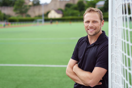 Fototapeta mann lehnt lächelnd an einem fußballtor auf dem sportplatz