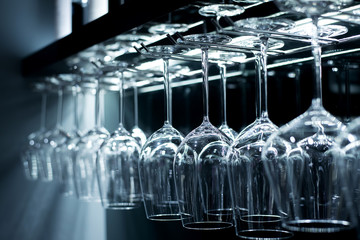 Group of empty wine glasses hanging from metal beams.