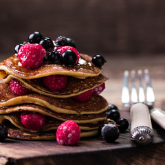 Buckwheat pancakes with berry fruit and honey on wooden vintage table