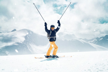 Gl&uuml;cklicher Skifahrer streckt die Skist&ouml;cke in die Luft