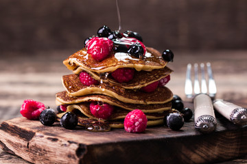 Buckwheat pancakes with berry fruit and honey on wooden vintage table