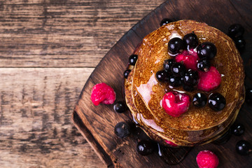 Buckwheat pancakes with berry fruit and honey on wooden vintage table