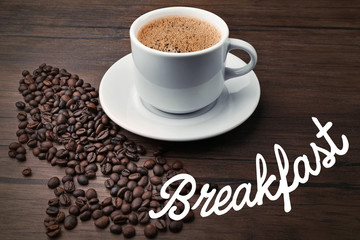 Word BREAKFAST and cup of aromatic coffee on wooden background