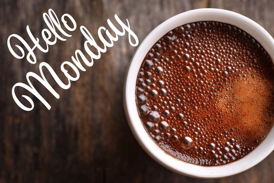 Text HELLO MONDAY and cup of aromatic coffee, closeup