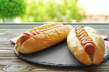Tasty hot dogs on round wooden board