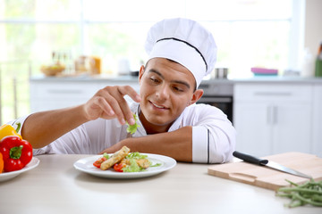 Young chef cook decorating meat dish in kitchen