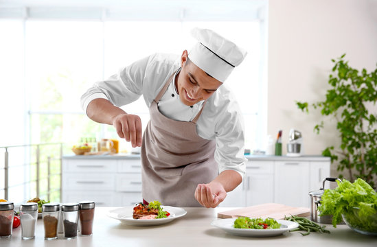 Young chef cook decorating meat dish in kitchen