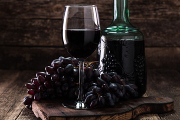 Glass of red wine, served with grapes on a wooden background