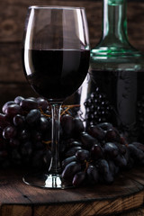 Glass of red wine, served with grapes on a wooden background