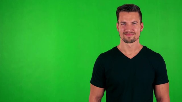 young handsome caucasian man smiles to camera - green screen - studio