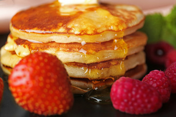 Tasty pancakes with berries and honey, closeup