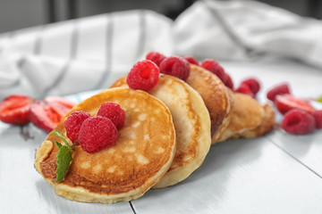 Tasty pancakes with berries and mint on wooden board