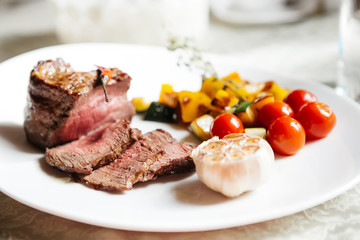 Steak medium rare with vegetable stew on a white plate