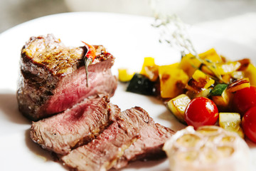 Steak medium rare with vegetable stew on a white plate
