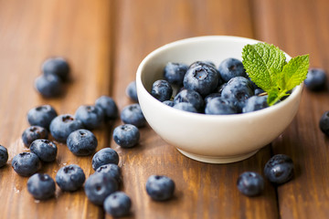 Blueberries in a white cup on a wooden background