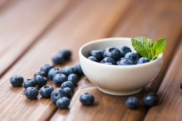 Blueberries in a white cup on a wooden background