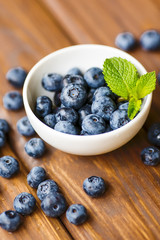 Blueberries in a white cup on a wooden background