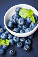 Blueberries in a white cup on a blue background