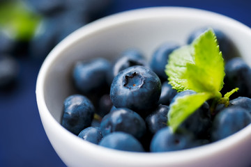 Blueberries in a white cup on a blue background