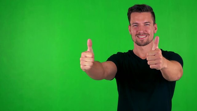 young handsome caucasian man shows thumbs up on agreement - green screen - studi