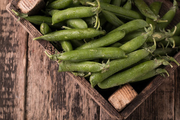 pods of green peas on a wooden table, rustic style,healthy food