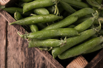 pods of green peas on a wooden table, rustic style,healthy food