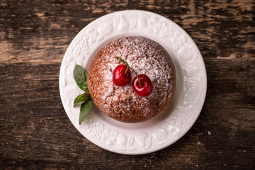 Tasty muffin with cherry and mint on vintage wooden background