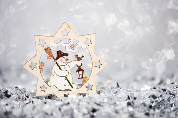 christmas wooden decor snowman in a star on glitter silver blurred background
