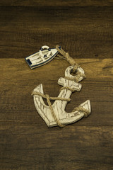 Small white ship with old large anchor on wooden background