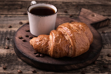 Breakfast with coffee and croissants on wooden vintage table