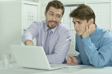 Naklejka na ściany i meble Two businessmen working on a laptop
