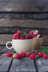 The concept of healthy eating fresh pink raspberry in a Cup on old wooden background with mint