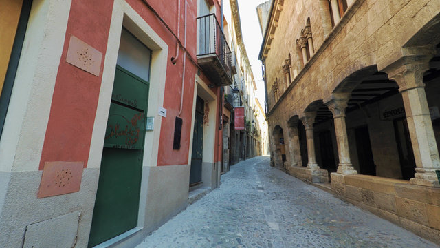 BESALU CATALONIA SPAIN - JULY 2016: Smooth camera steady wide angle shot along narrow street in the old european spain village goes up, high colorful ancient walls with windows, clear sky with sun