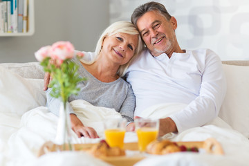 Obraz na płótnie Canvas Senior couple enjoying breakfast in bed 