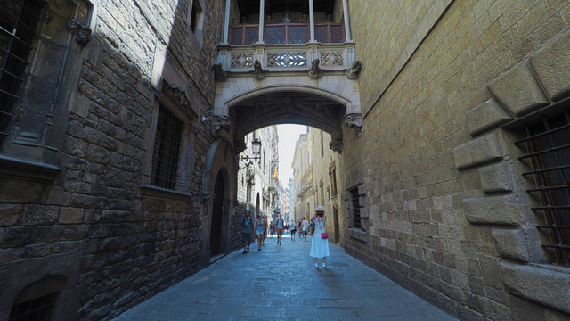 BARCELONA CATALONIA SPAIN - JULY 2016: Smooth camera steady shot along narrow street in the center of barcelona, near to gothic quarter, clear blue sky with sun shining, tourists slowly walking along