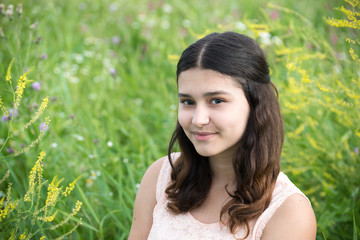 Naklejka premium The girl with dark hair on background of green grass
