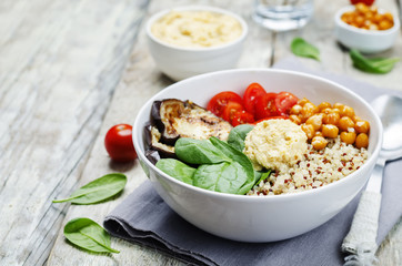 Mediterranean quinoa hummus bowl with eggplants, tomatoes and sp