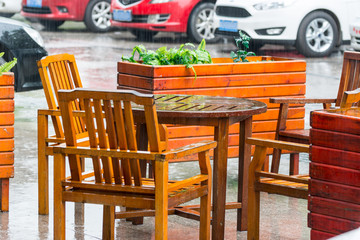 Wooden tables and chairs at the outside of restaurant under raining 