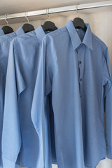 row of blue color shirts hanging on rail