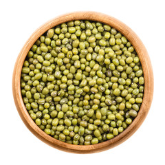 Mung beans in a wooden bowl on white background. Dried beans of Vigna radiata, also moong bean, green gram or mung, a legume, used in cuisine as ingrdient and to sprout. Isolated macro food photo.