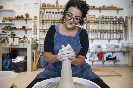 Woman working with a potter's wheel in a ceramics workshop