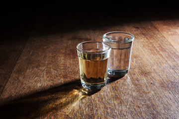 Shot glasses of Brazilian cachaca isolated on rustic wooden background