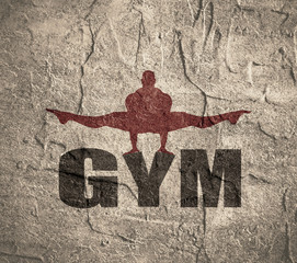 Muscular man posing on gym word. Concrete texture. Bodybuilding relative image