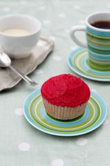 Home made red cupcake on a green plate with coffee and cream
