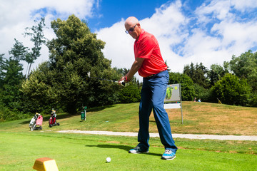 Senior man doing tee stroke on golf course