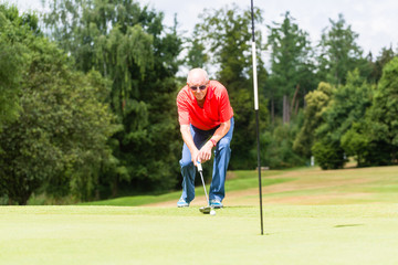 Senior golf player aiming his stroke to the hole